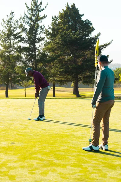 Joven Caucásico Con Bandera Golf Amigo Afroamericano Golpeando Pelota Golf —  Fotos de Stock