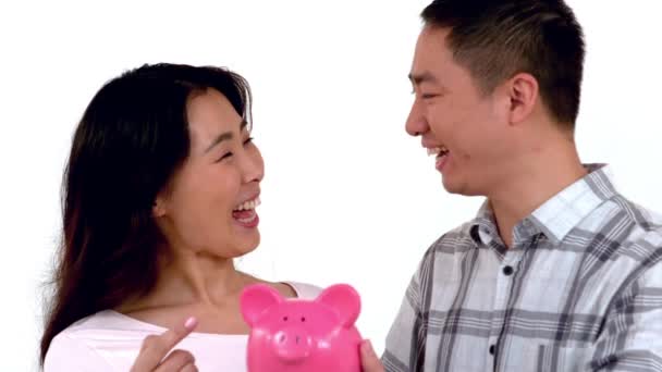 亚洲夫妇互相亲吻白色背景时 按住一个存钱罐 — 图库视频影像