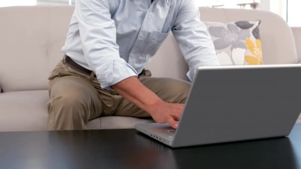 男人坐在沙发上在家时使用笔记本电脑 — 图库视频影像