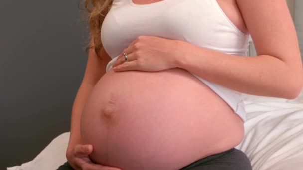 怀孕的女人坐在床上摸她的肚子在家里 — 图库视频影像