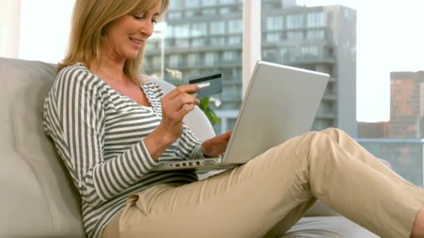 女人用她的笔记本电脑上网购物 并且坐在沙发上用慢动作 — 图库视频影像