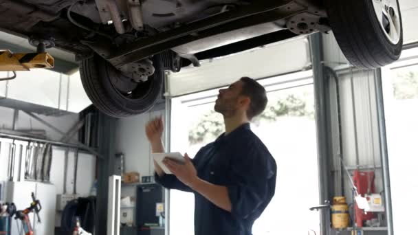 英俊的机械师检修一辆车在他的车库里 — 图库视频影像