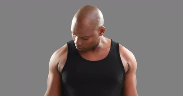 灰色の背景上でダンベルを持ち上げて深刻な筋肉男 — ストック動画