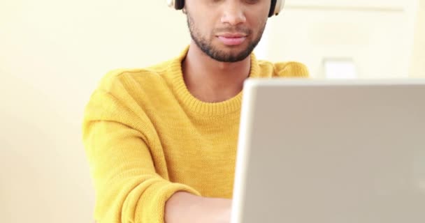 Χαμογελαστός Άνθρωπος Ακουστικά Χρησιμοποιώντας Φορητό Υπολογιστή Στο Σπίτι — Αρχείο Βίντεο