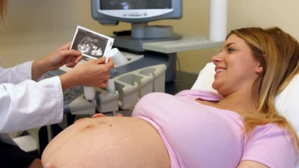 医師は妊娠中の女性に彼女の超音波スキャン画像を表示 — ストック動画
