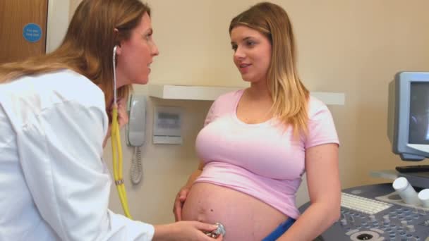 妊娠中の梨花の胃に聴診器を使用して赤ちゃんをチェックする医師 — ストック動画