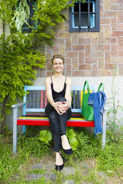 Bankta oturan genç gülümseyen kadın — Stok fotoğraf