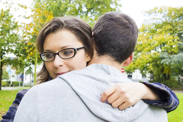 Portret van liefde paar omarmen buiten in park op zoek gelukkig — Stockfoto