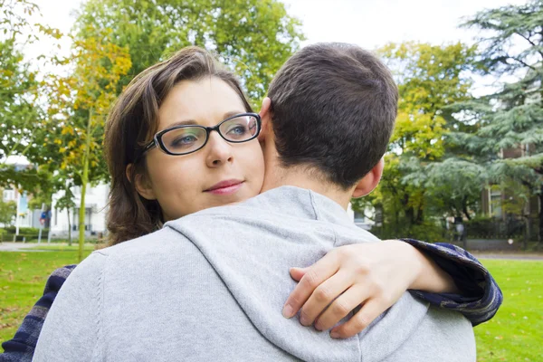 Retrato de casal de amor abraçando ao ar livre no parque olhando feliz — Fotografia de Stock