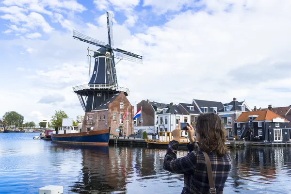 Tourist girl is taking pictures of traditional Dutch windmill — Stock Photo, Image