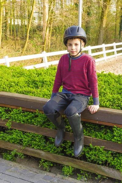 ヘルメットとブーツ n 座っている乗馬のためのかわいい 10 代の少年 ストックフォト