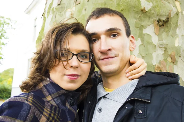 Retrato de casal de amor abraçando ao ar livre no parque olhando feliz — Fotografia de Stock