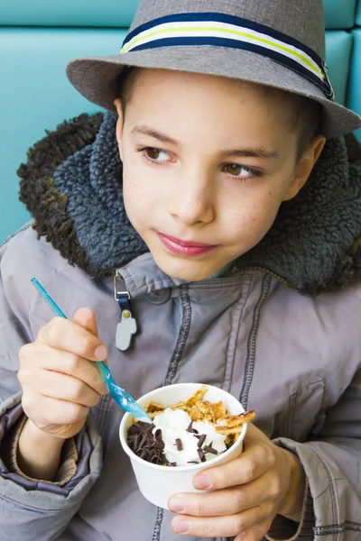 Cute teenage boy eating ice cream with chocolate topping — Stock Photo, Image