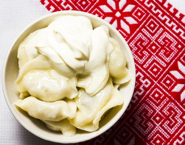 Dumplings with sour cream on the Ukrainian embroidered towel — Stock Photo, Image