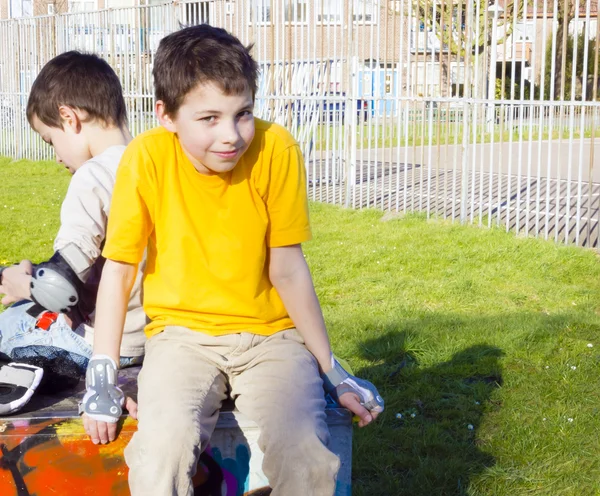 Två söta pojkar i roller-blading skydd kit sitter i lekplat — Stockfoto