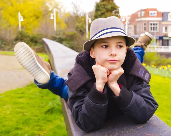 Cute teenage boy lying on the parapet at the park — Stock Photo, Image