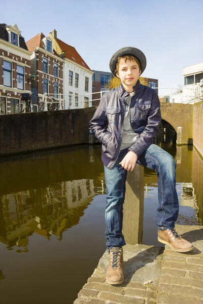 Cute teenage boy in hat (full-length portrait) against canal bac — Stock Photo, Image