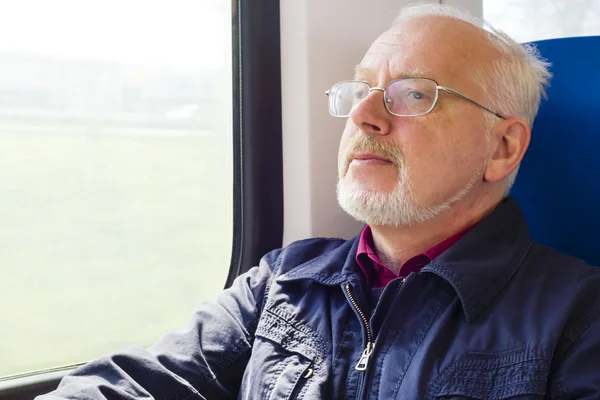 Relaxed old man sitting near the window in the carriage — Stock Photo, Image