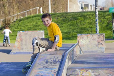 silindir-blading koruma seti içinde bir paten gülümseyen genç çocuk