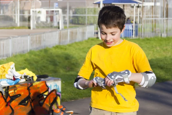 O menino coloca em kit de proteção de rolo atentamente — Fotografia de Stock