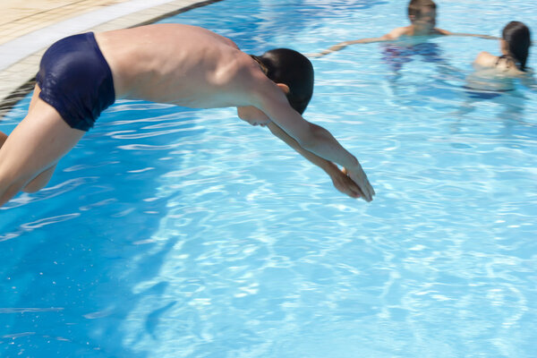 Ажиотаж в бассейне. Симпатичный мальчик плавает и играет в воду i
