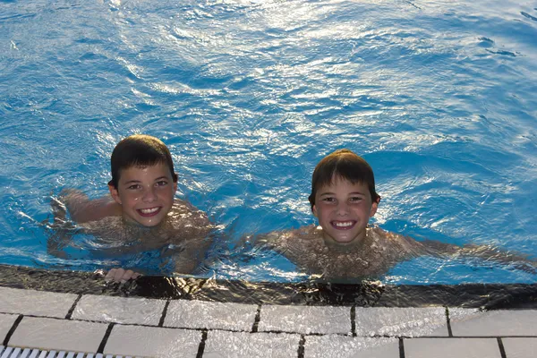 Atividades na piscina. Bonitos meninos nadando e brincando na água — Fotografia de Stock