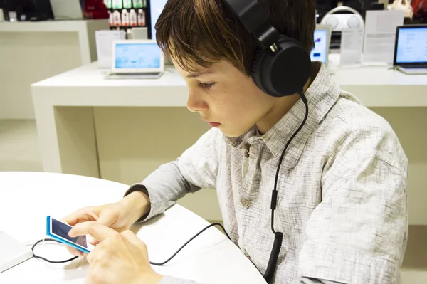 Porträtt av en söt ung pojke lyssna på musik i hörlurar — Stockfoto