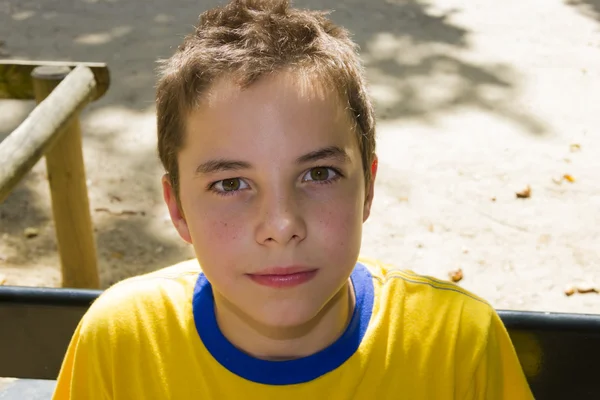 Cute boy smiling at camera in the park on a sunny day — Stock Photo, Image