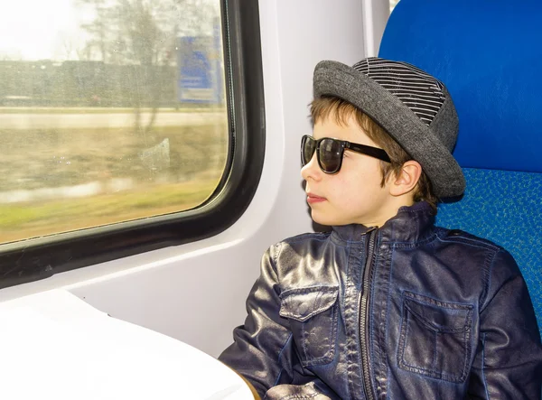 Chico guapo en gafas de sol monta en un tren — Foto de Stock