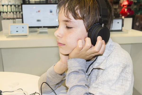 Porträtt av en söt ung pojke lyssna på musik i hörlurar — Stockfoto