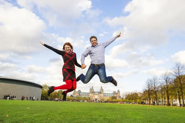 Casal feliz ao ar livre saltando em Museumplein, Amsterdam — Fotografia de Stock