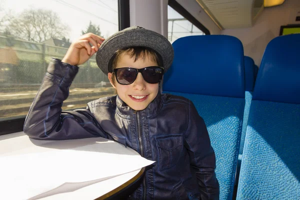 Chico guapo con gafas de sol monta en un tren leyendo del papel — Foto de Stock