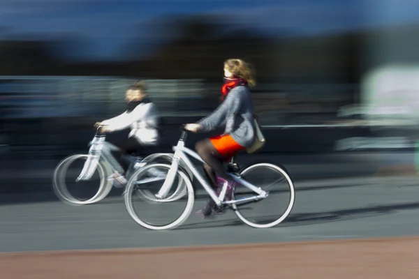 Zwei Frauen auf den verschwommenen Fahrrädern im Profil — Stockfoto