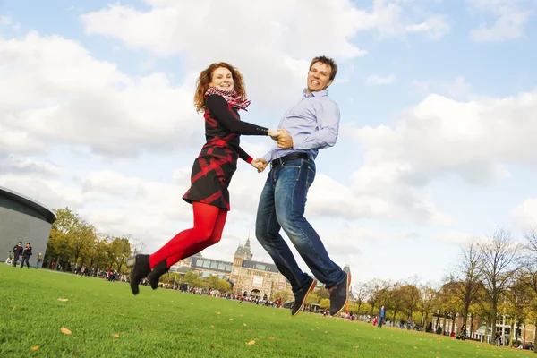 Outdoor happy couple jumping in Museumplein, Amsterdam — Stock Photo, Image