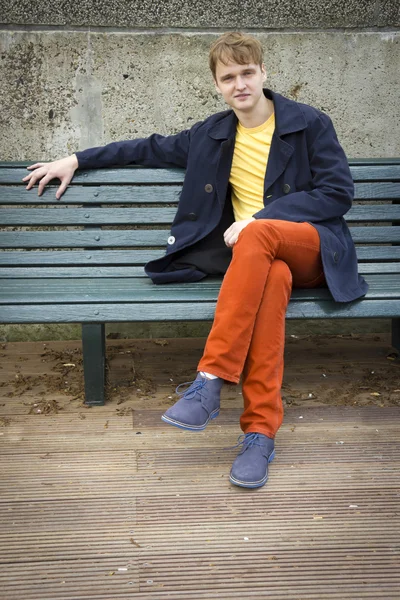 Handsome young man sitting on a bench. Candid. — Stock Photo, Image