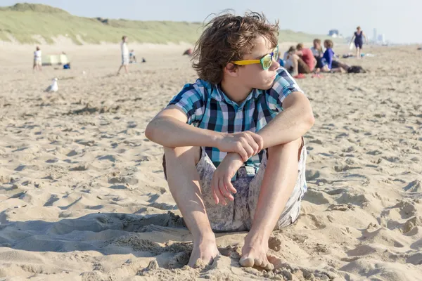 Porträt eines Teenagers, der auf Sand sitzt — Stockfoto