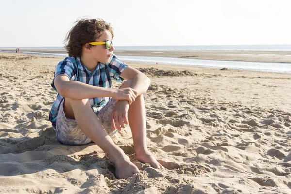 Ragazzo adolescente seduto sulla spiaggia — Foto Stock