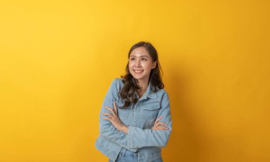 Asyalı mutlu, günlük kıyafetlerle gülümseyen bir kadın kameraya bakıyor ve sarı arka plandaki yazı için fotokopi alanıyla kesişiyor. Reklam konsepti.