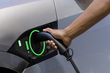EV Car. şöför elini elektrik kablosu ile doldur elektrikli araç şarj istasyonu, EV şarj istasyonu, yeşil enerji, mavi enerji, elektrik enerjisi, teknoloji ve EV araba konsepti