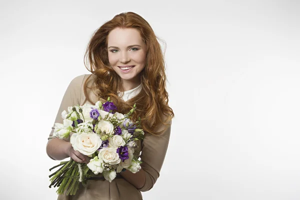 Bela menina sorridente com um buquê de flores em um fundo branco — Fotografia de Stock