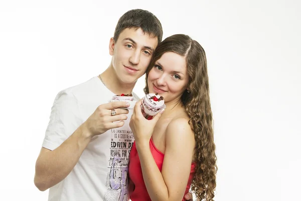 Happy young couple with cakes on white background — Stock Photo, Image