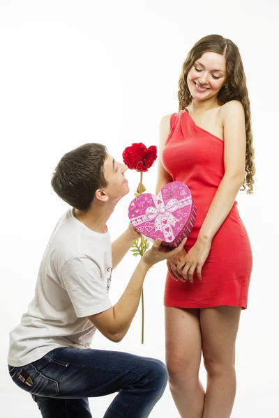 Glückliches junges Paar auf weißem Hintergrund. glücklicher Mann schenkt seiner Freundin ein Geschenk — Stockfoto