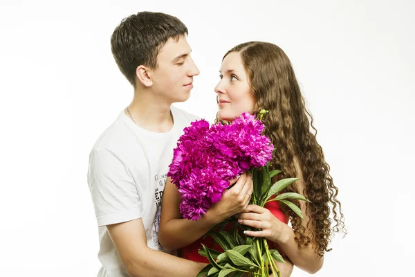 Schönes junges Liebespaar auf weißem Hintergrund mit einem Blumenstrauß — Stockfoto