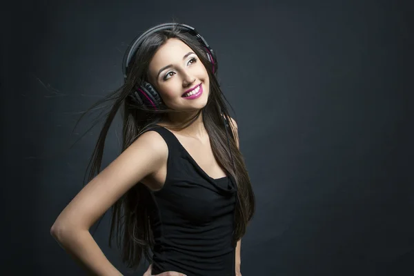 Portrait of a young smiling girl with headphones listening to music — Stock Photo, Image