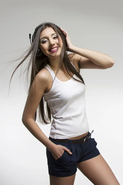 Portrait of a young smiling girl with headphones listening to music — Stock Photo, Image