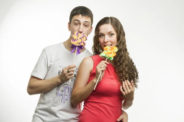 Jovem casal feliz com pirulitos coloridos no fundo branco Imagens De Bancos De Imagens