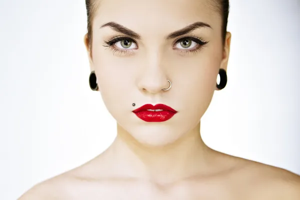 Schöne Punkerin mit Tätowierungen, Piercings, rotem Lippenstift und perfekter Haut Stockfoto