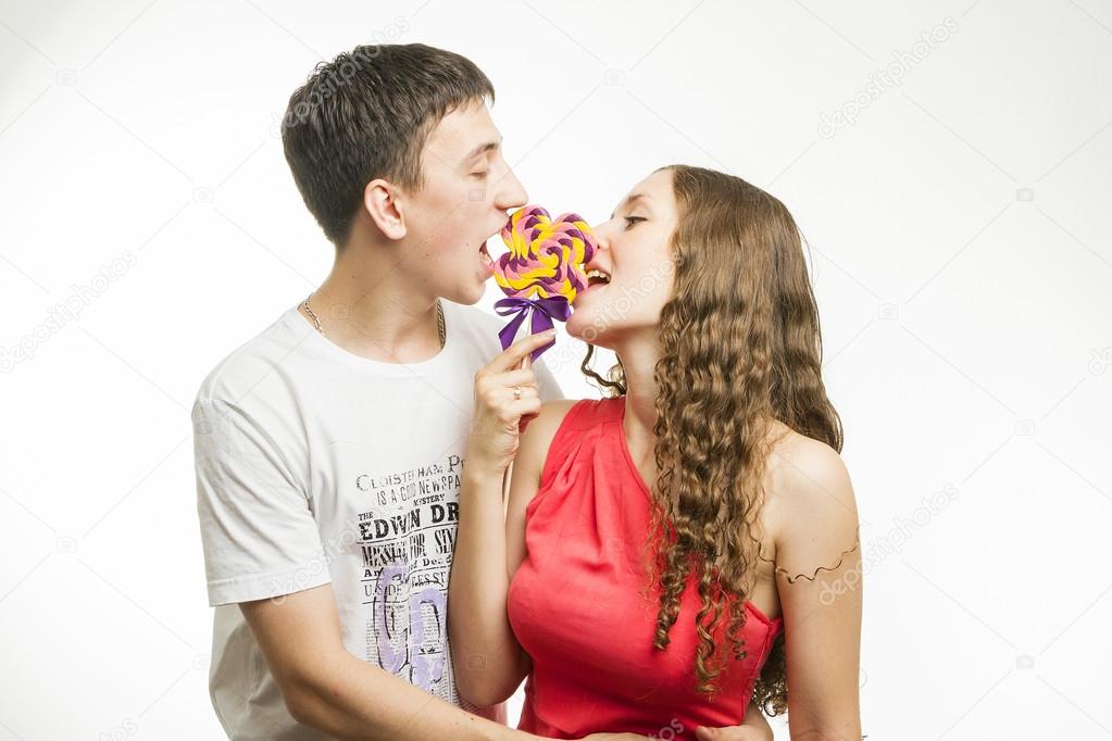 Happy young couple with colorful lollipops on white background
