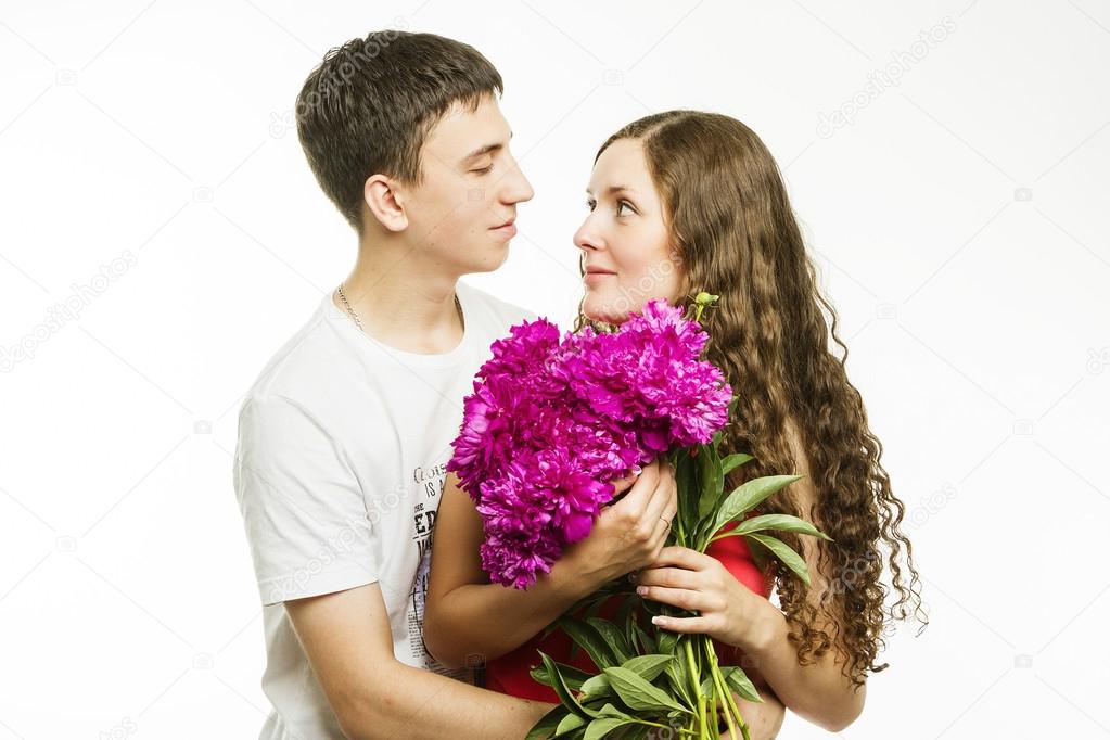 Beautiful young love couple on a white background with a bouquet of flowers