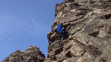Uçurumun tepesinde bir adam bir çıkıntıyı yakalamaya çalışıyor.